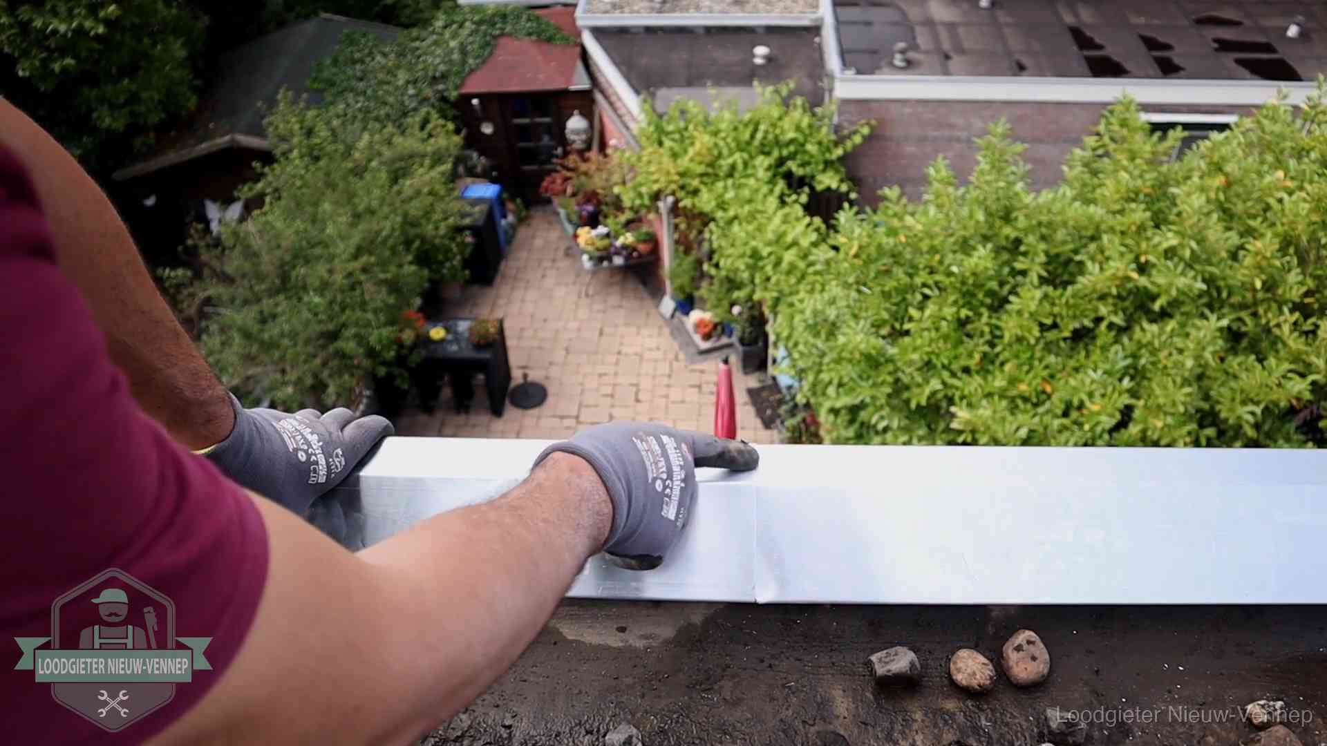 Vakman plaatst een daktrim op de dakrand van een woning in Nieuw-Vennep