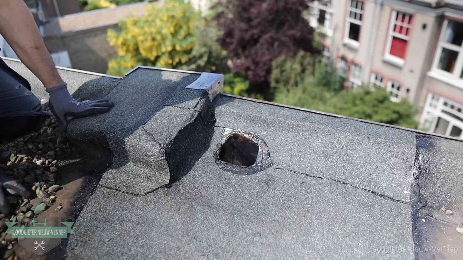 Loodgieter inspecteert een beschadigd bitumen plat dak tijdens een daklekkage-inspectie in Nieuw-Vennep