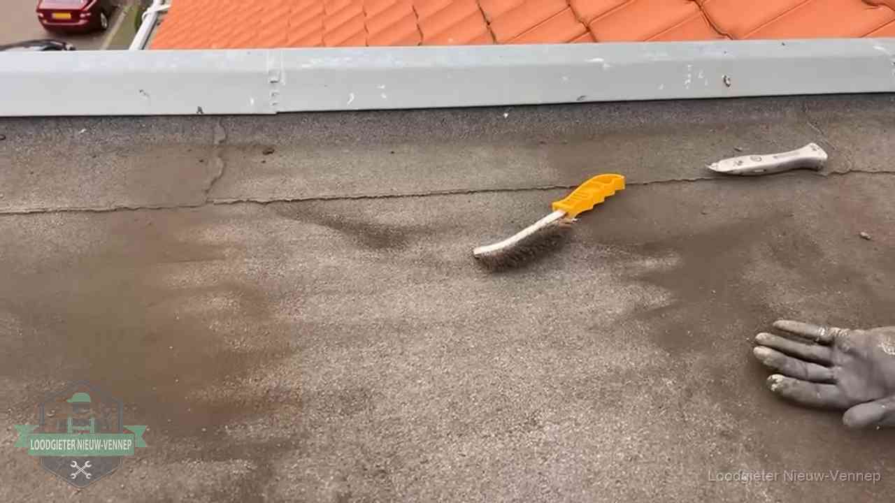 Dakdekker bereidt een bitumen plat dak voor op reparatie bij de daktrim in Nieuw-Vennep