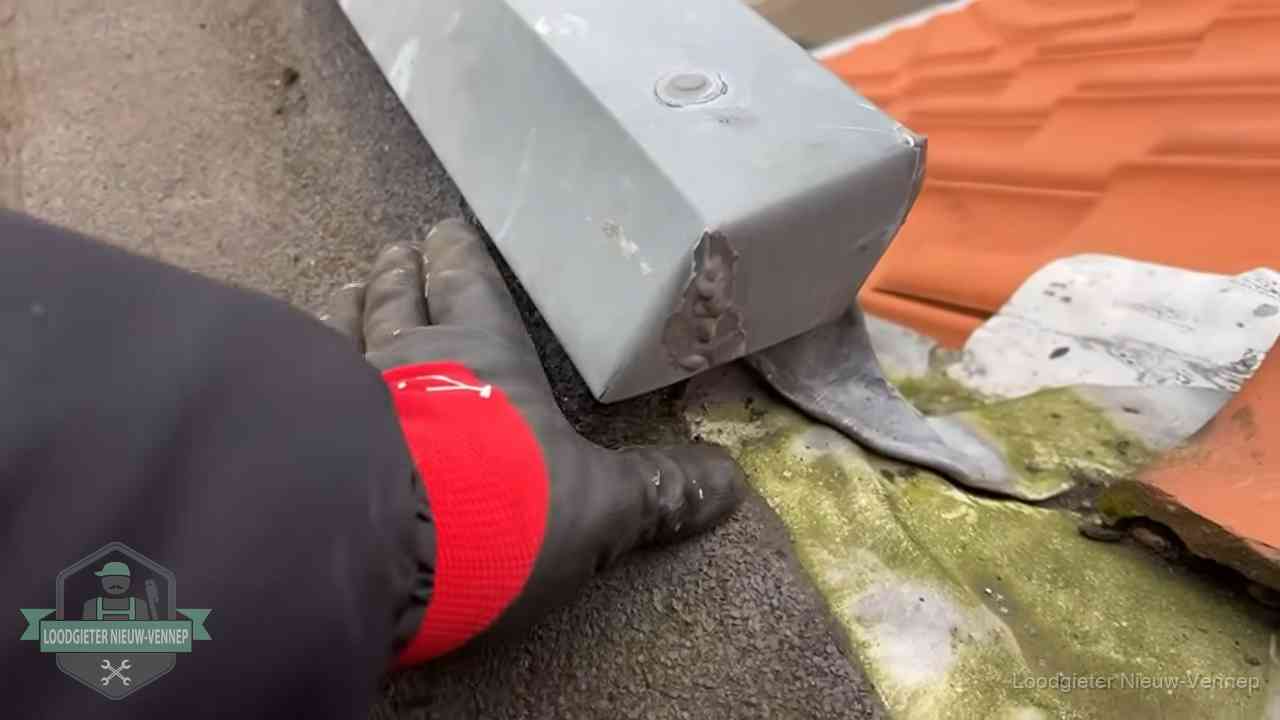 Controle van een zinken hemelwaterafvoer met loodslab bij dakpannen in Nieuw-Vennep