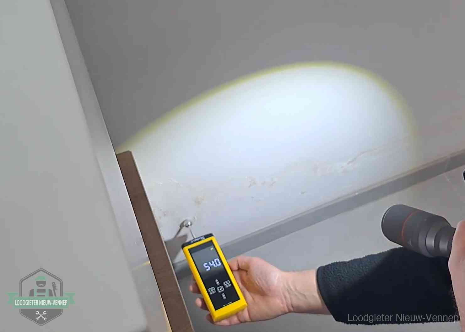 Vochtmeter tegen een natte wand met lekkagesporen in Nieuw-Vennep