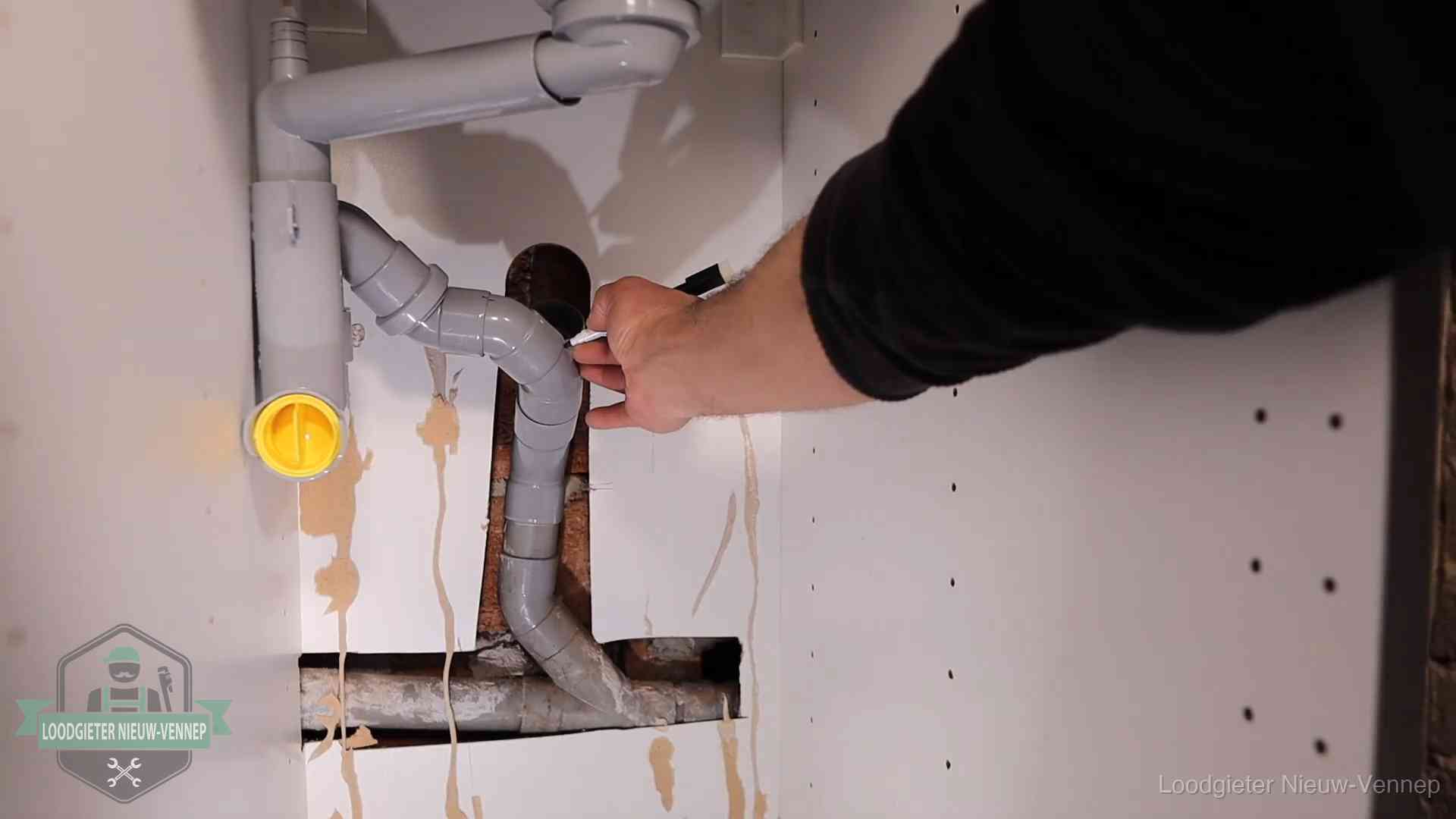 Loodgieter voor verhuurders en bedrijven in Nieuw-Vennep Loodgieter markeert een pvc-afvoerbuis onder een gootsteen in Nieuw-Vennep