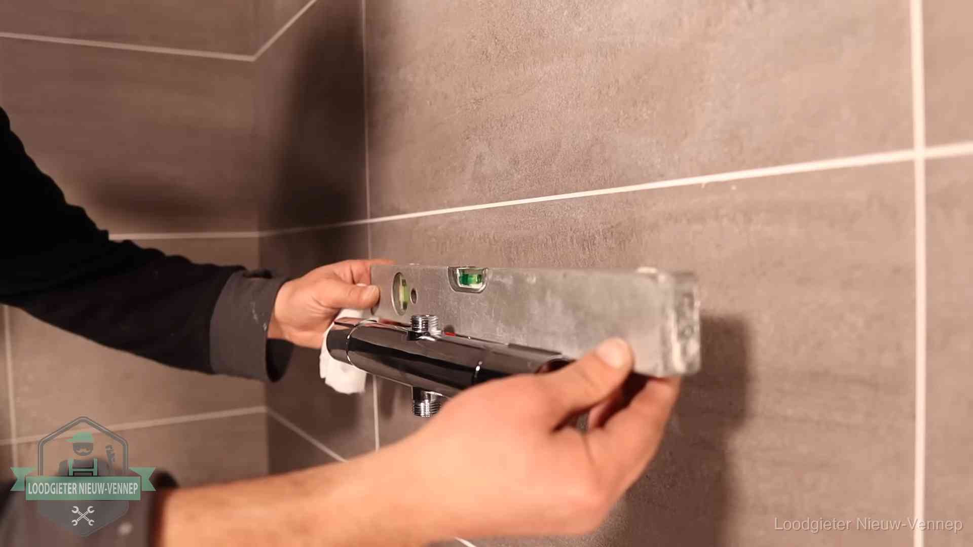 Loodgietersbedrijf voor sanitair in Nieuw-Vennep Loodgieter lijnt een douchekraan uit met een waterpas in een woning in Nieuw-Vennep