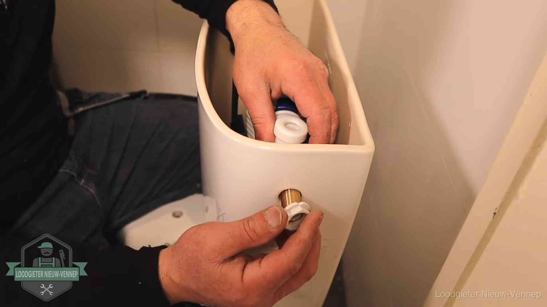 Loodgieter monteert de vlotterkraan van een stortbak bij een toilet in Nieuw-Vennep