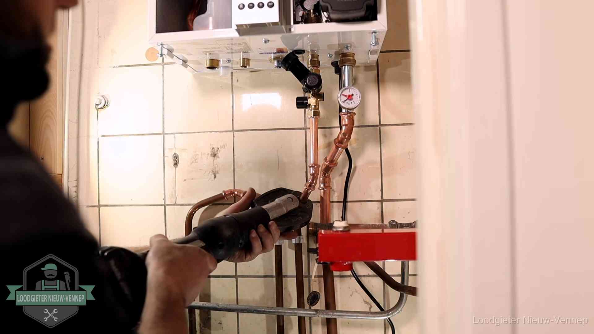 Monteur werkt aan de leidingen onder een cv-ketel in Nieuw-Vennep