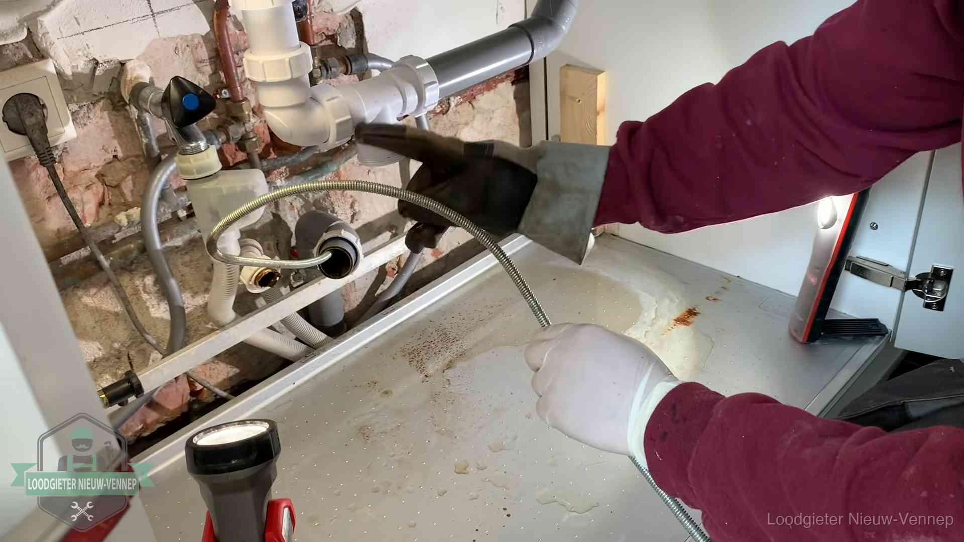 Spiraal of hogedruk in Nieuw-Vennep Ontstoppingsveer gaat in een geopende sifonaansluiting onder het aanrecht in Nieuw-Vennep
