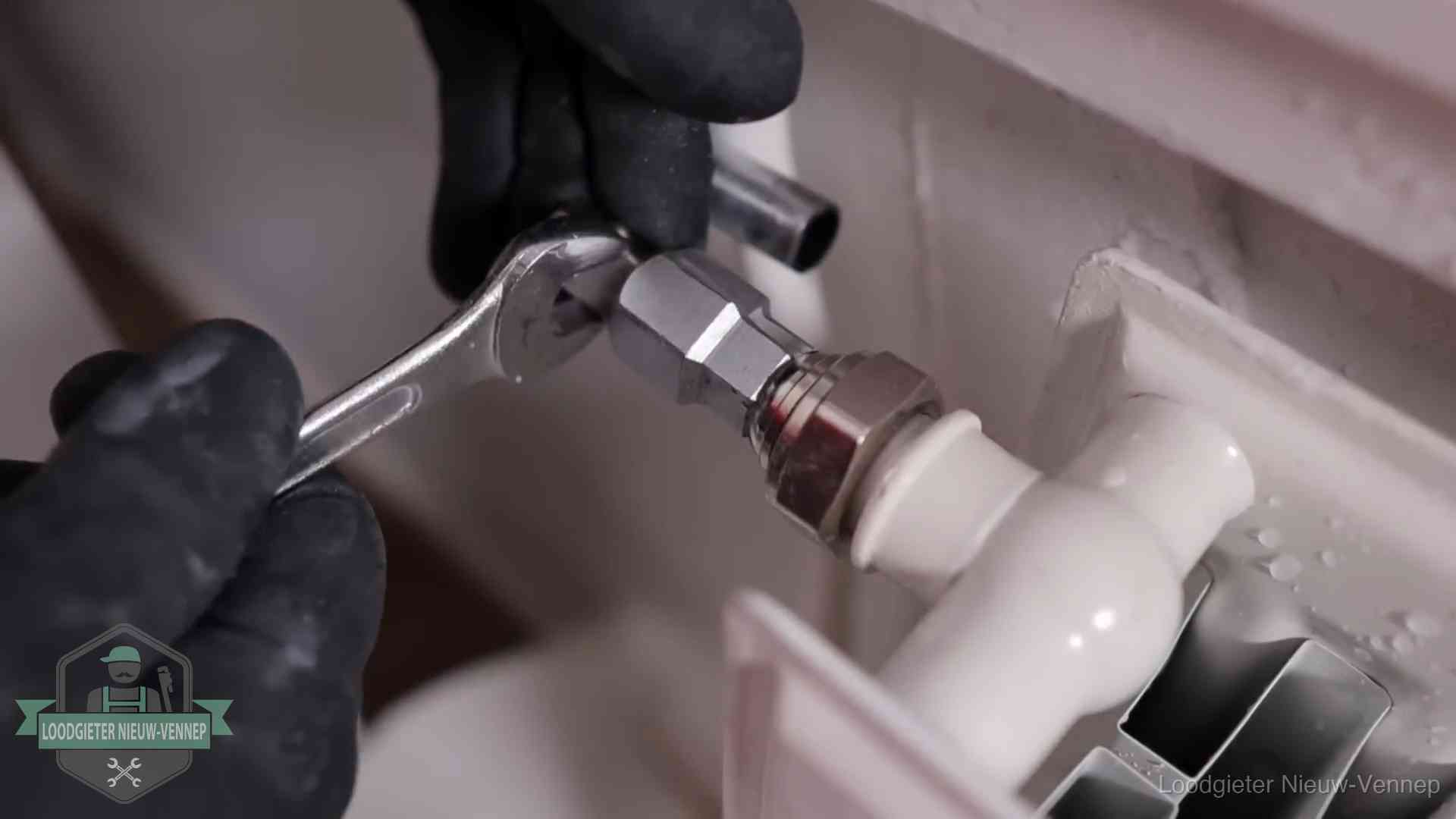 Steeksleutel draait een wartelkoppeling op een radiatorkraan aan in Nieuw-Vennep
