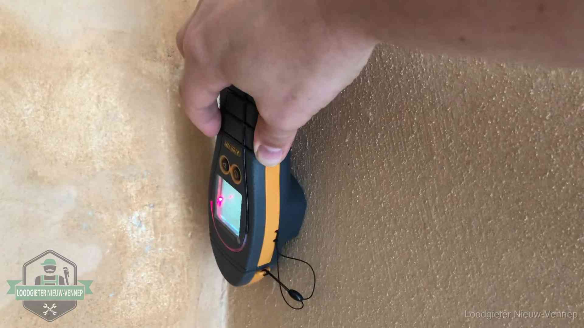 Vochtmeter tegen een muur met vochtplekken tijdens het opsporen van een daklekkage in Nieuw-Vennep